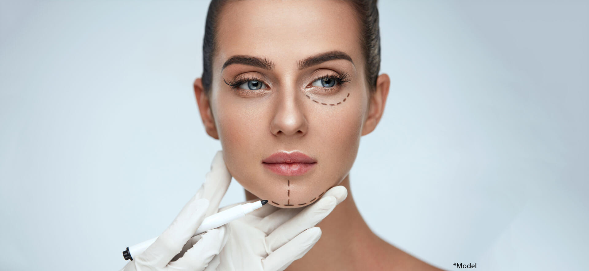 Beautician drawing surgical lines on woman face