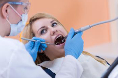 Dentist drilling a tooth of young woman