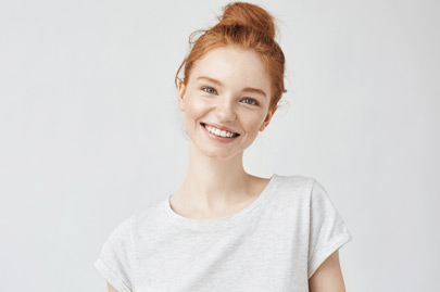 Headshot Portrait of happy ginger girl with freckles smiling looking at camera