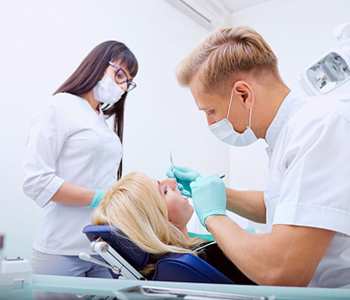 Male dentist with his assistant treating a patient