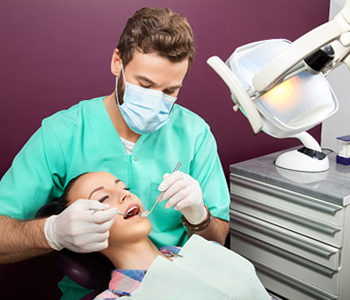 Male dentist examines mouth of a woman on the dentist's chair